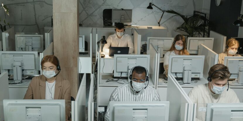 Multicultural team wearing masks in a call center managing customer support during the day.