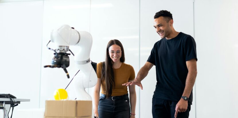 Two engineers collaborating on testing a futuristic robotic prototype in a modern indoor lab.